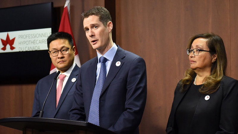 Paul Taylor, Elaine Taylor, and Dong Lee Speaking at podium in front of house