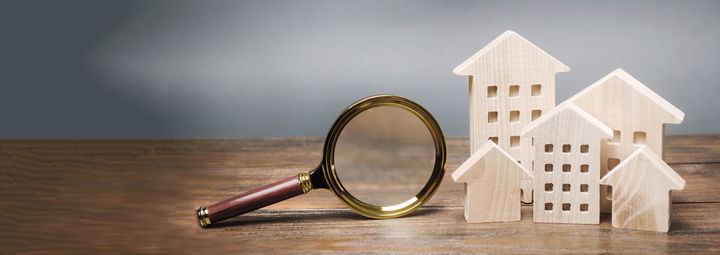 Magnifying glass with some wooden toy houses and apartments